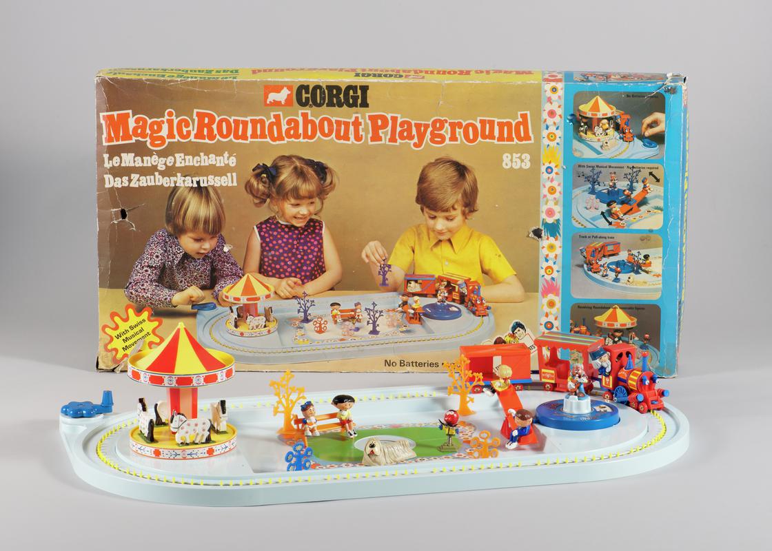 Original box for Magic Roundabout Playground set and Pale blue plastic base for Magic Roundabout Playground set, with mechanicaly operated see-saw and hand operated railway track. Magic Roundabout model in three parts consisiting of base with four horses, column and canopy. Roundabout sits on base 2000.179/2 with all Parts and Characters