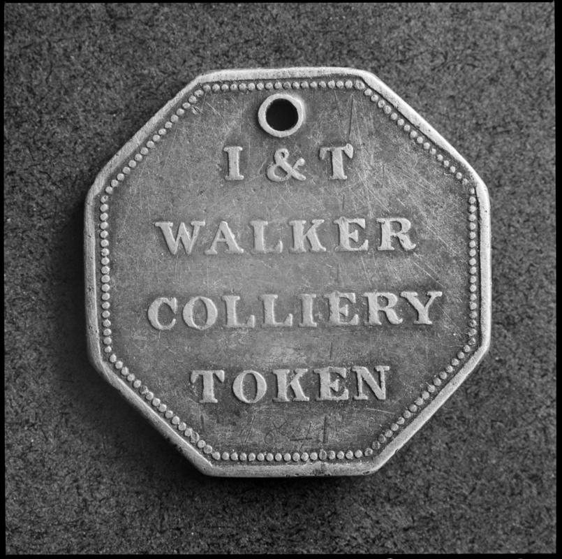 Black and white film negative showing an I &amp; T Walker Colliery Token.