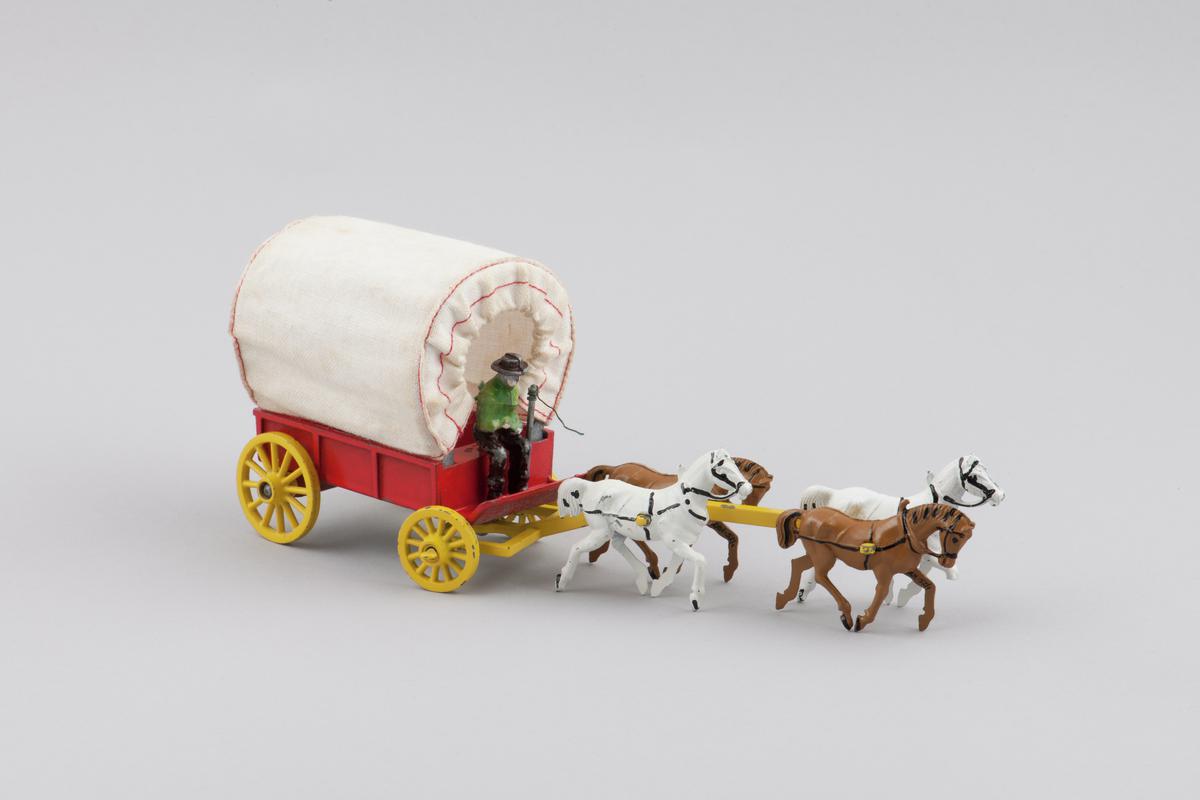 Red, cloth covered wagon with yellow wheels, pulled by four detachable horses. Detachable driver and whip. original box  is (2001.52/2).