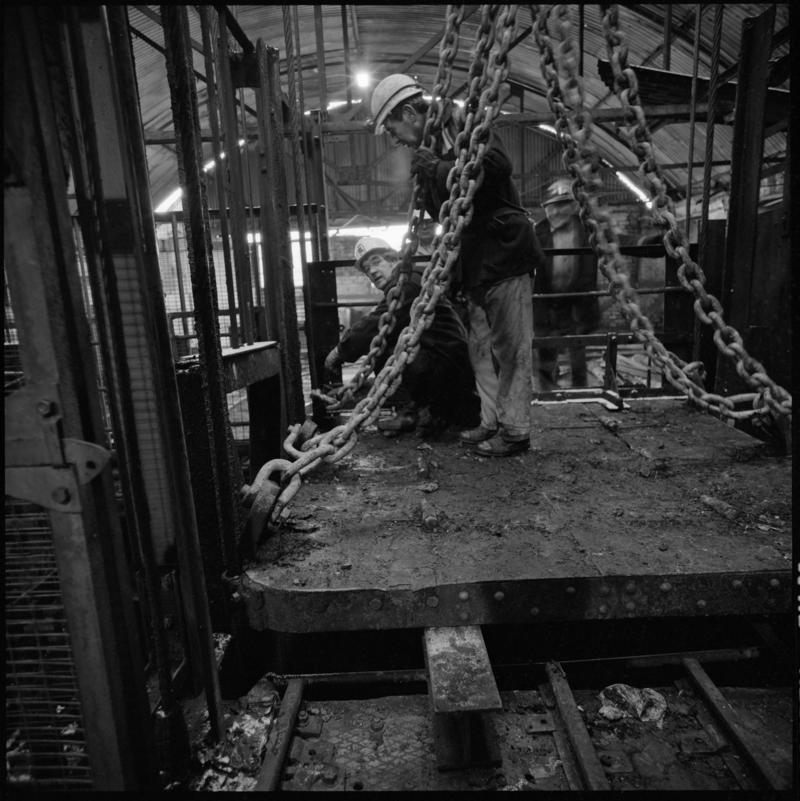 Black and white film negative showing man standing on top of cage at pit top, Big Pit Colliery January 1982.  &#039;Big Pit Blaenavon Jan 1982&#039; is transcribed from original negative bag.