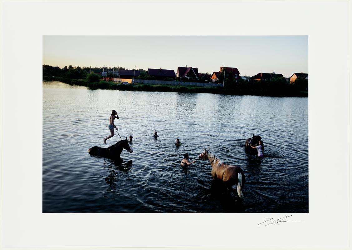 Girls bathing their horses in a swimming pond next to an upscale dacha community. Vyarki, near Bykovo. Russia