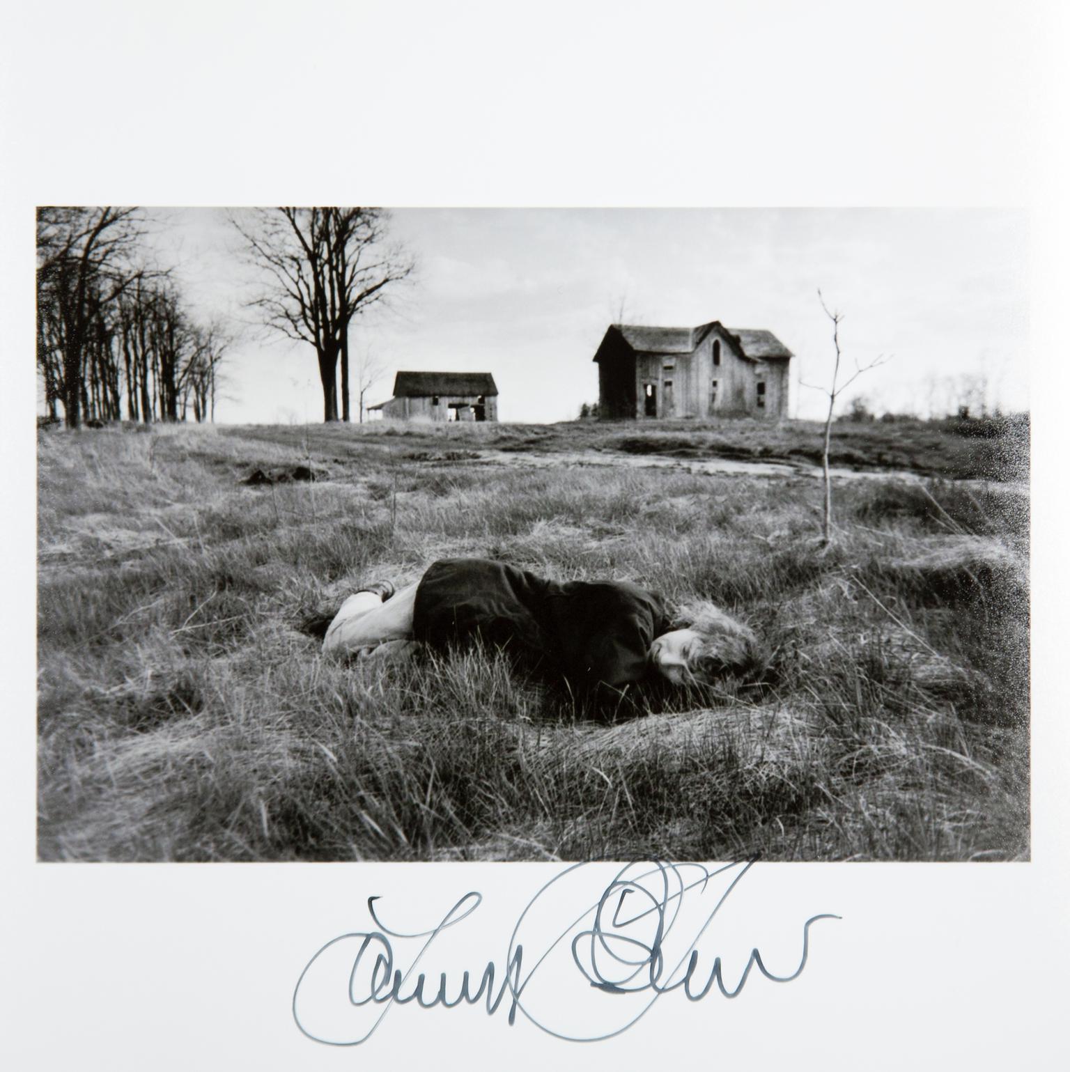 Ann Towell lies in the grass to rest on a spring day in front of an abandoned pioneer house and barn in rural Ontario