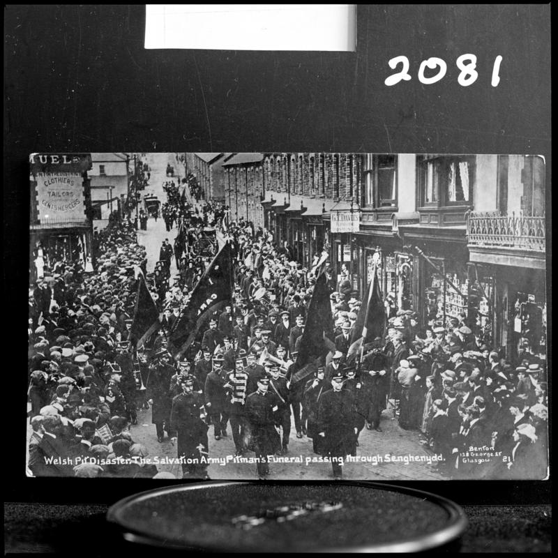 Black and white film negative of a photograph showing a funeral procession passing through Senghenydd.  Caption on photograph reads &#039;Welsh Pit Disaster. The Salvation Army Pitman&#039;s funeral passing through Senghenydd&#039;.
