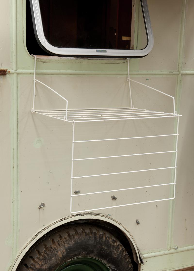 Plastic coated metal clothes hanger dryer suspended from window in caravan.