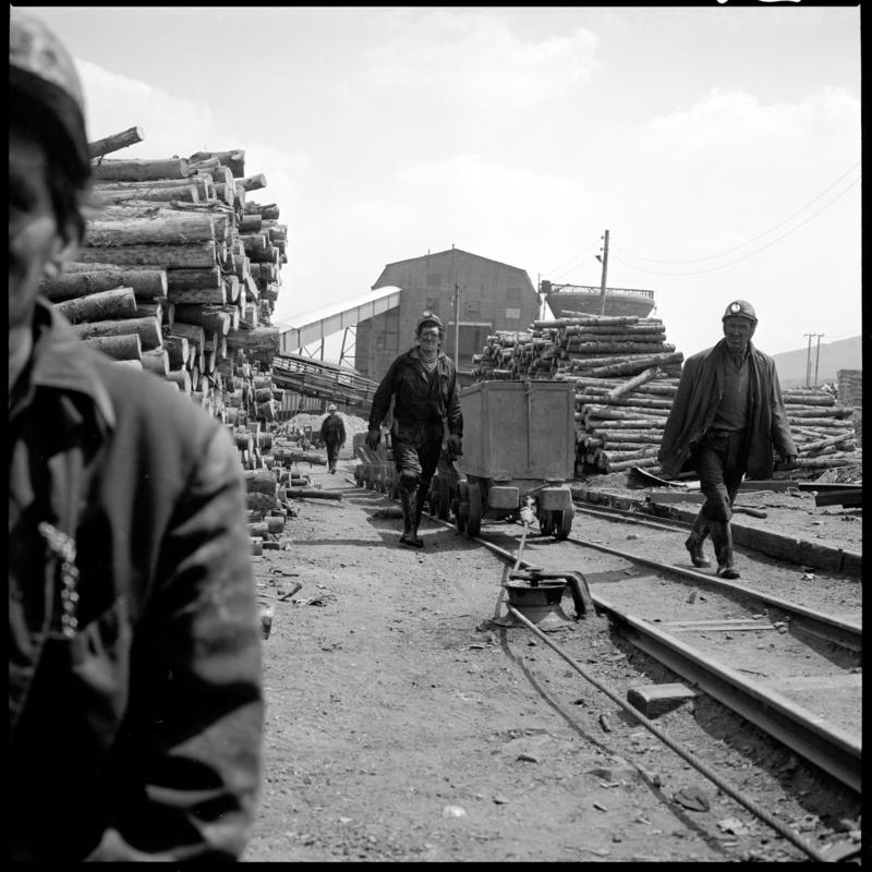 Black and white film negative showing miners in the timber yard at the end of their morning shift, Big Pit.