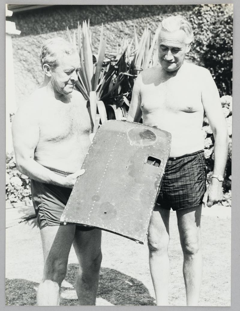 Photograph of Joe Rees and unidentifies man with piece of aircraft.