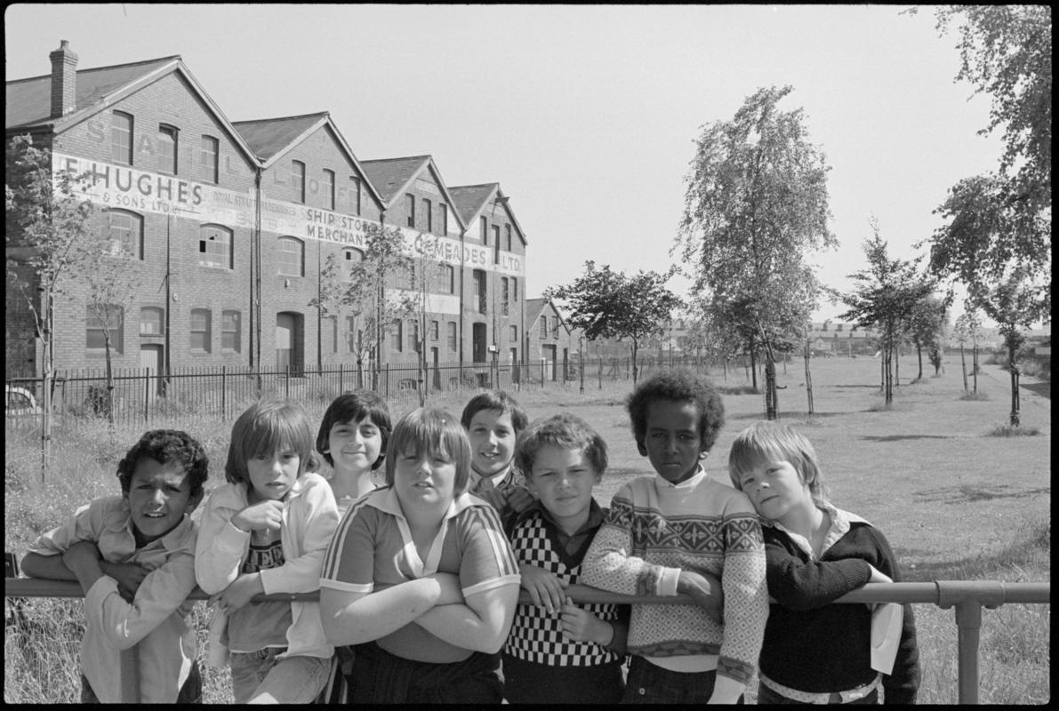 Group of children with old warehouses and site of the Glamorganshire Canal in the background.
