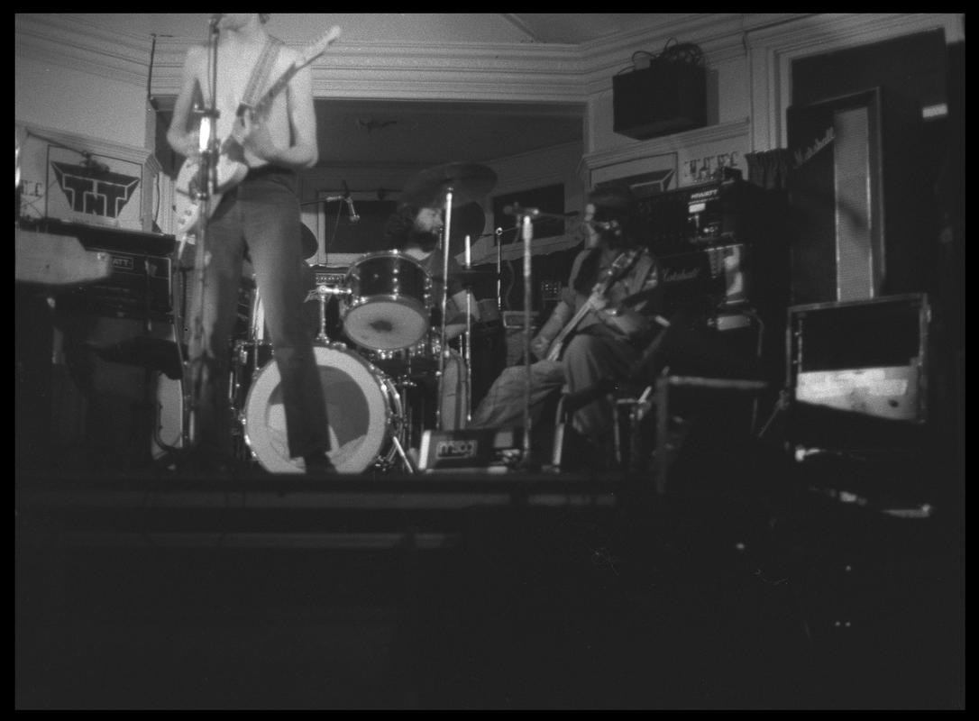 Guitarist and other members of TNT Group on stage. Location unknown.