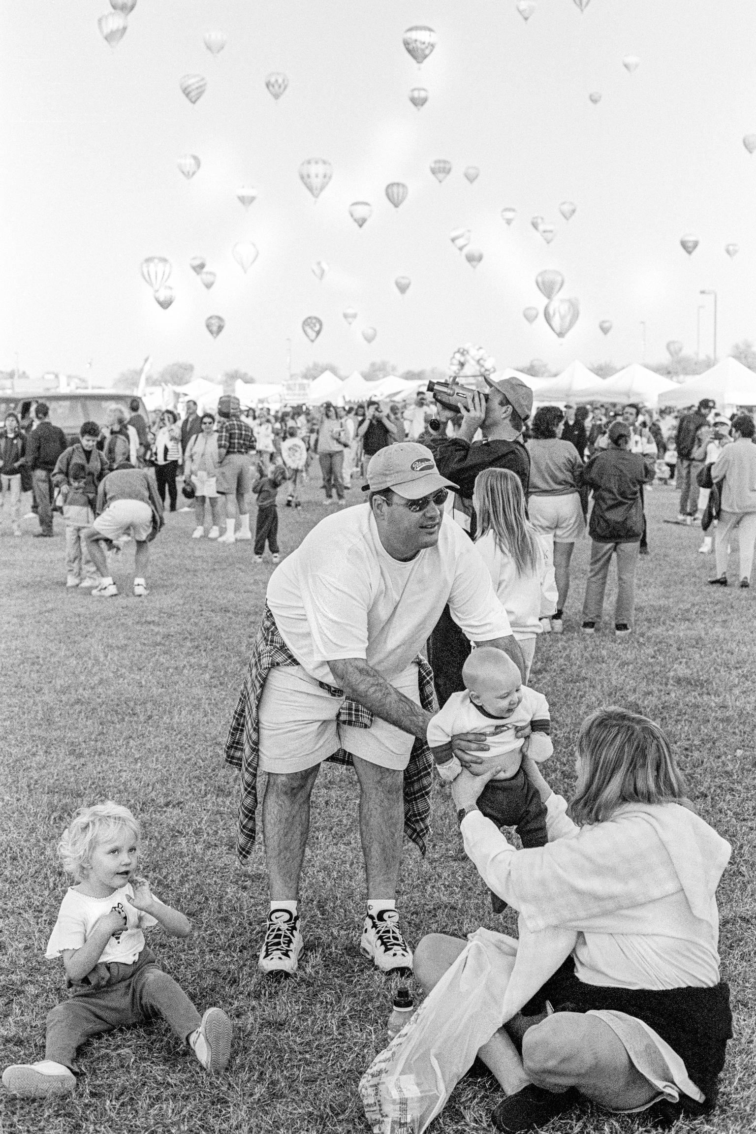 Phoenix Balloon Rally. Family group enjoying a day out in the sun. Hundreds of Balloons fly in the background. Phoenix, Arizona USA