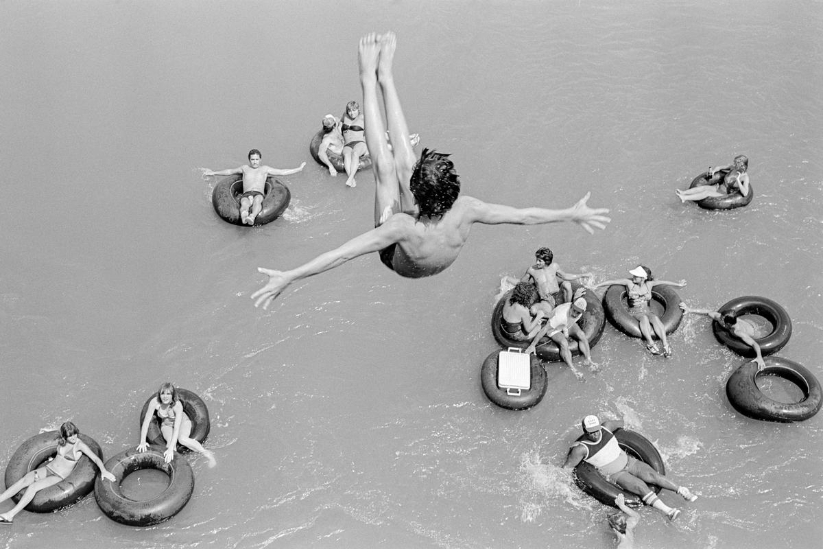 USA. ARIZONA.  Salt City. At the height of summer one of the favourite activities of the mainly young is tubing.  This consists of gently drifting down the river (Salt River) over the many miles of the course and spending up to six hours in the sun.  Much drink and suntan lotion is taken. 1980.