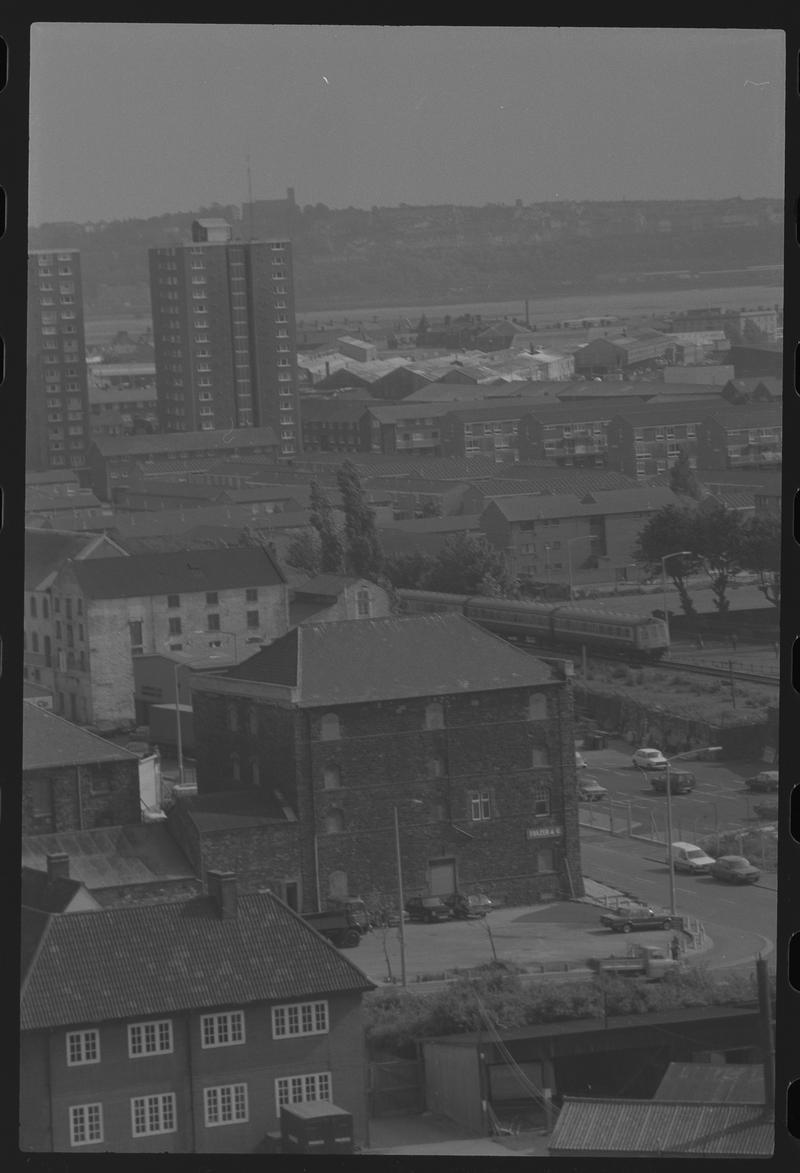 View of Herbert Street and Collingdon Road, with passenger train on right, flats on left, and St Augustines Church and Penarth in background.