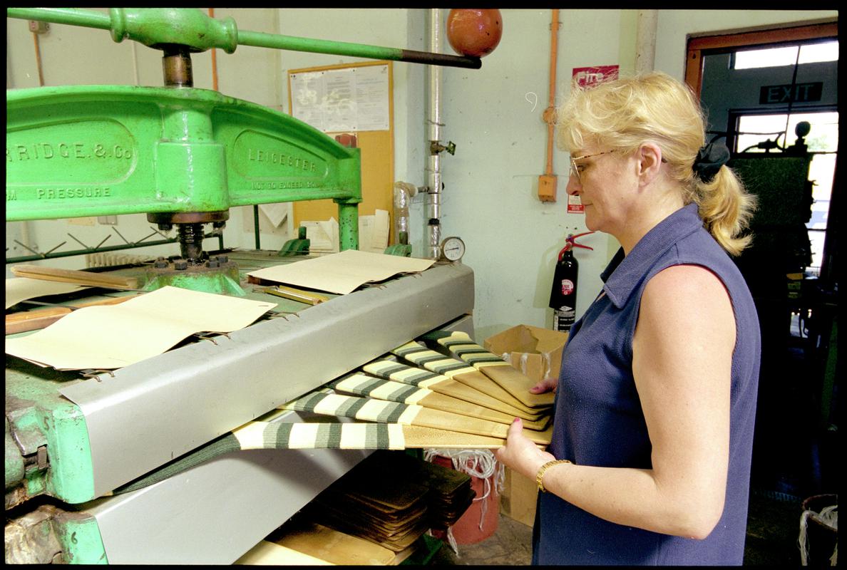 Diane Phillips removing a set of sock from a steam pressing machine at Corgi Hosiery Ltd factory, Ammanford, 1 July 2002.