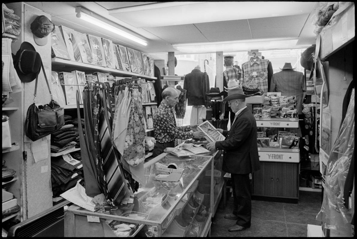 Interior view of &#039;Maurice Merchant Navy General Outfitter&#039;, 5 James Street, Butetown, showing the proprietor Mr M. Colpstein serving merchant seaman Mr T. Szarota. This was the last remaining outfitters in Cardiff Dockland.
