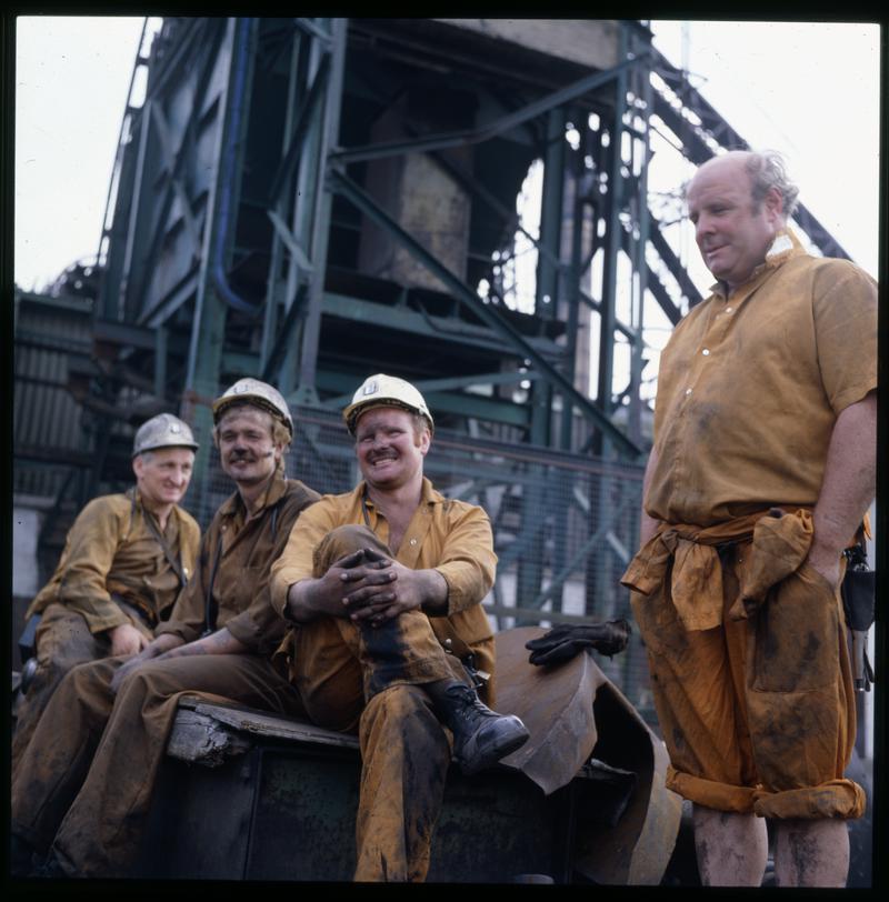 Four miners in the yard with headgear in the background, Lewis Merthyr Colliery