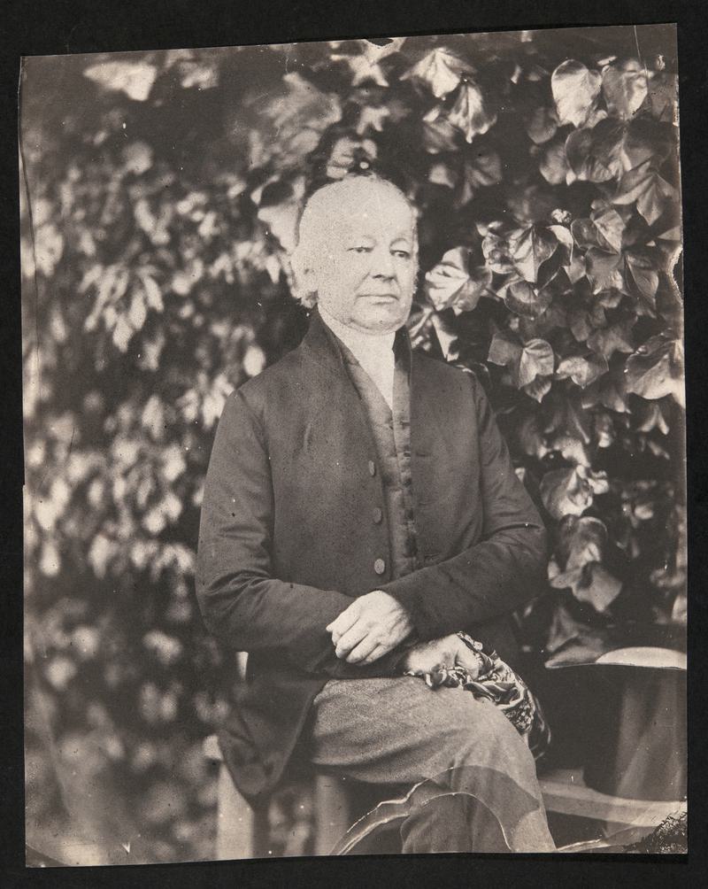 Gentleman seated in garden, photograph