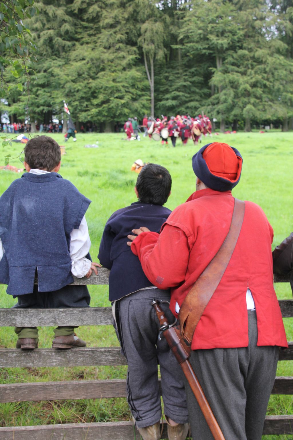 Older and younger re-enactors watch a battle display