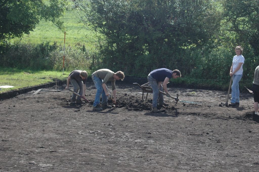 Four students use mattocks to start a new trench.