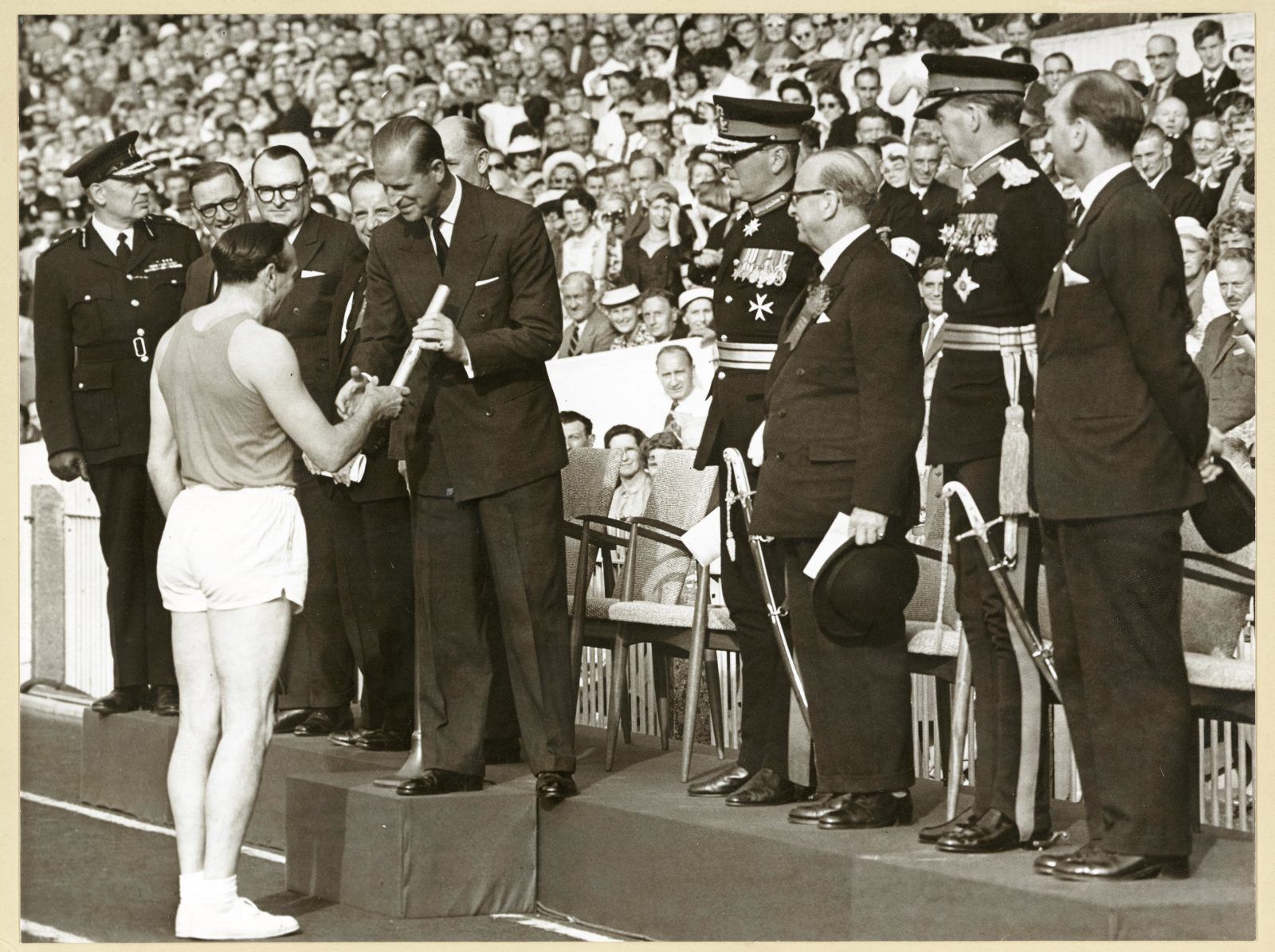 Ken Jones, former Wales rugby player and Olympic athlete, presenting the baton to the Duke of Edinburgh at the opening ceremony at Cardiff Arms Park. (© Commonwealth Games Federation)