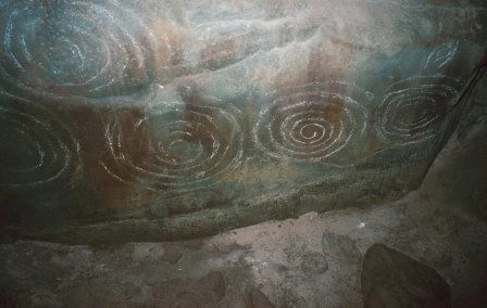 Carved stone inside the chamber of Barclodiad y Gawres (Anglesey). The style of carving in this passage tomb is common to many tombs in Ireland.
