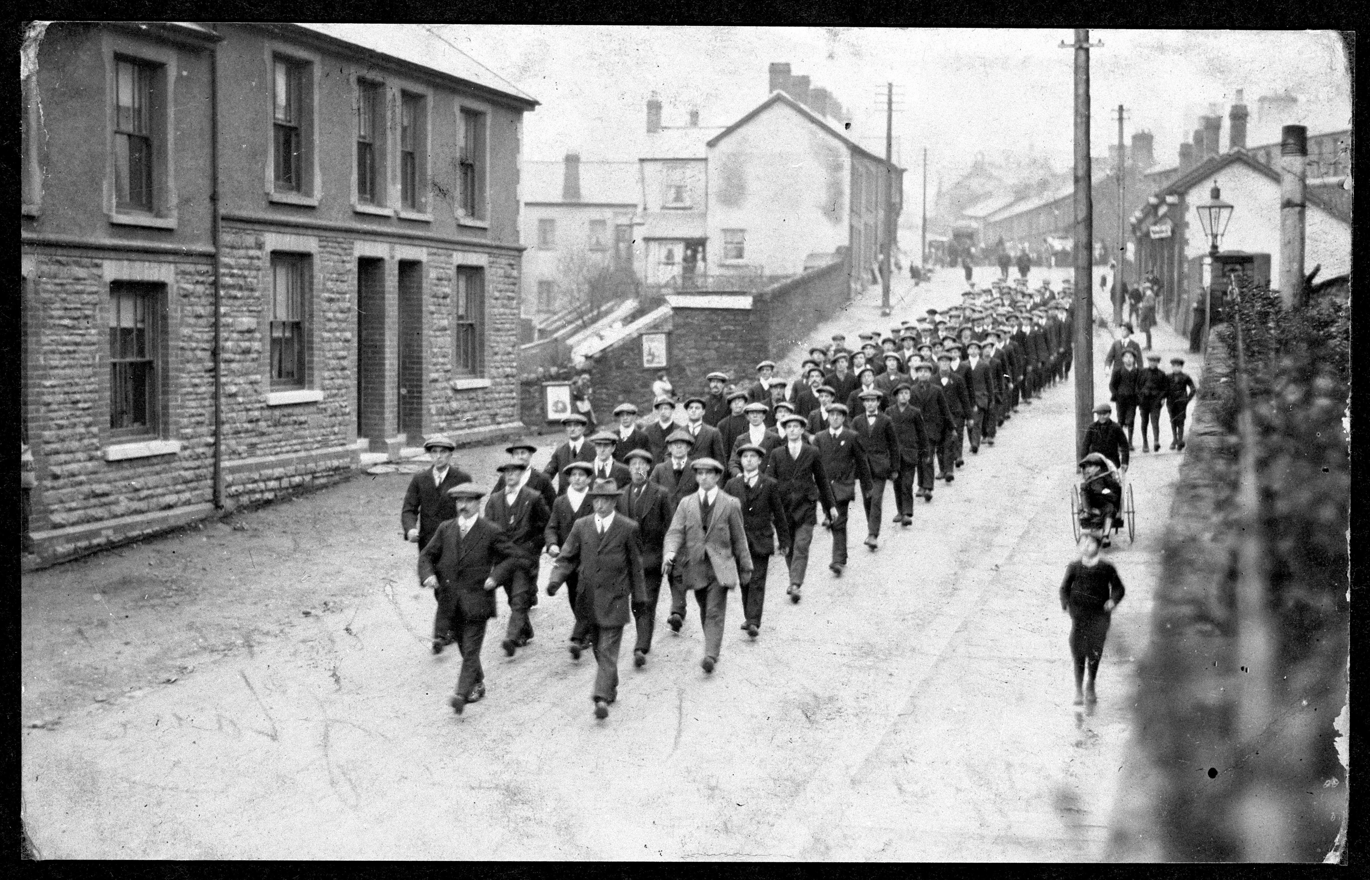 New recruits in civilian clothes marching in a column down a street in Rhondda