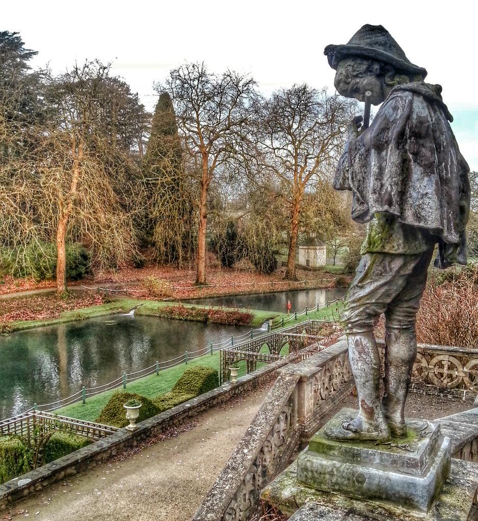 A picture of a statue of a piper over looking St Fagans ponds