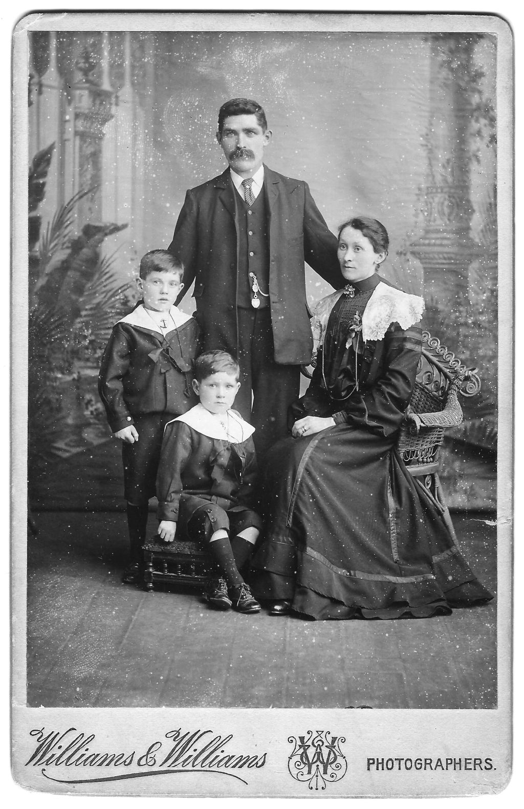 Studio portrait of the Edmunds family in about 1905. The father stands behind his wife and two children.