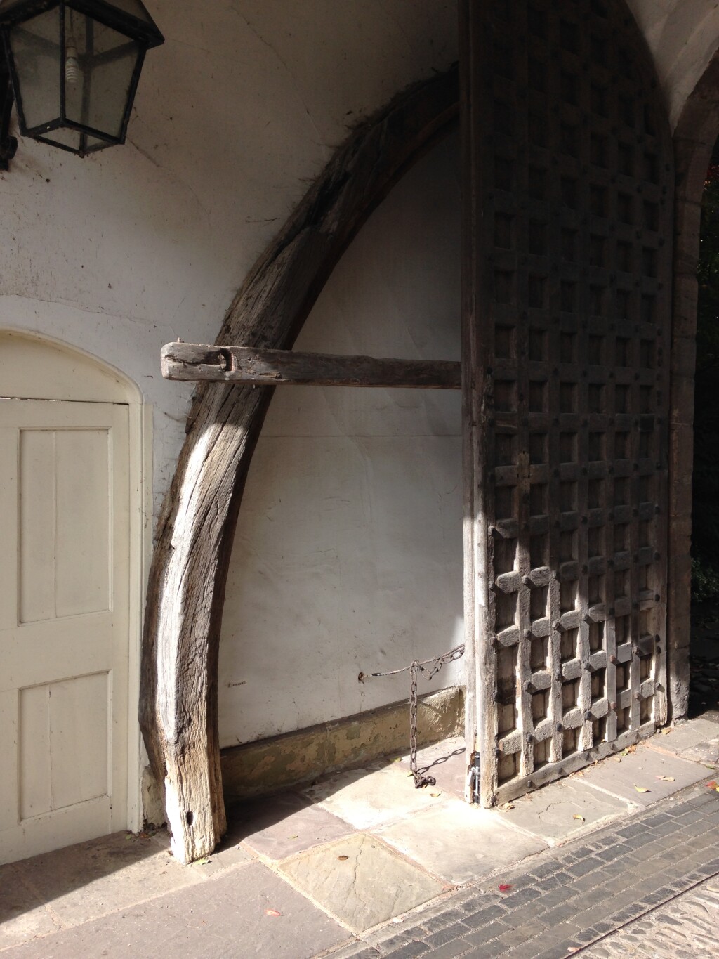 A wooden arched brace leaning against the wall of a porch