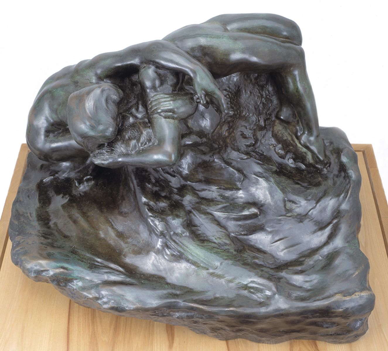 A bronze sculpture by Rodin showing two human figures twisting and contorting in a vague, cloud-like shape