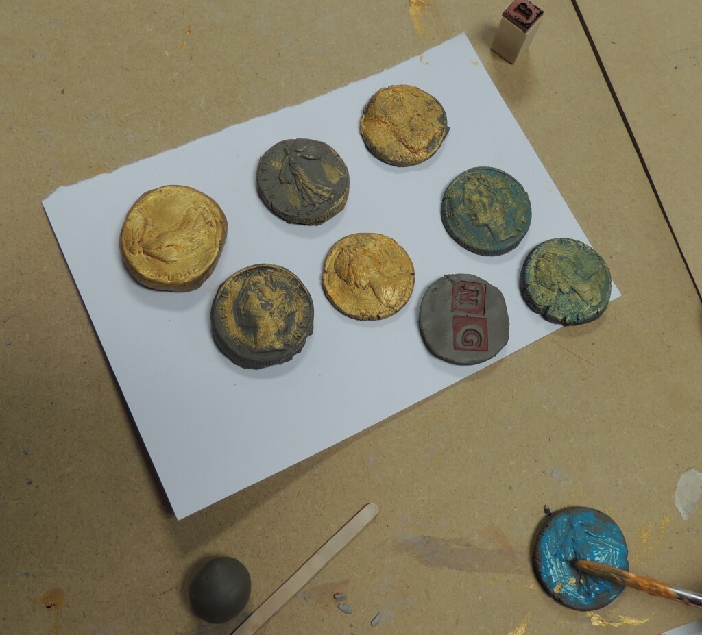 Some coins made out of modelling clay and painted with gold paint made at a children's workshop.