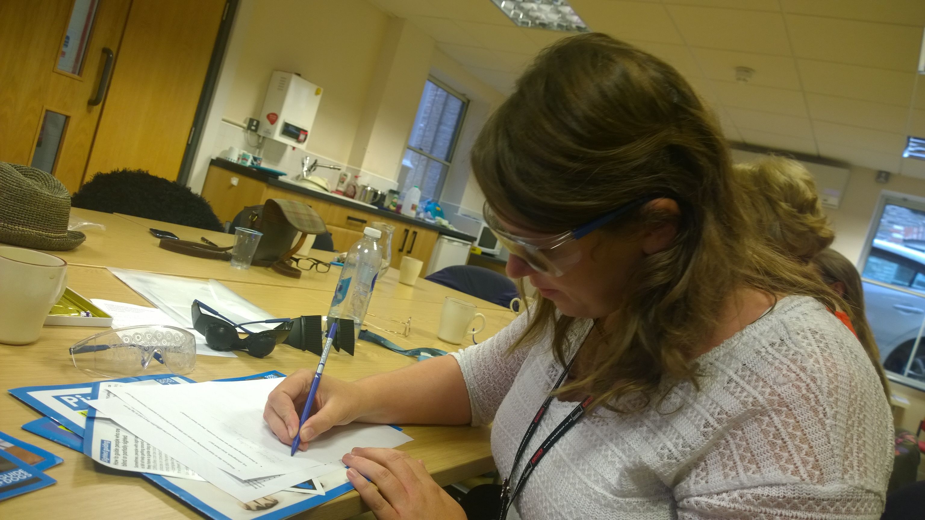 A female member of Museum staff writing while wearing a pair of simi-specs