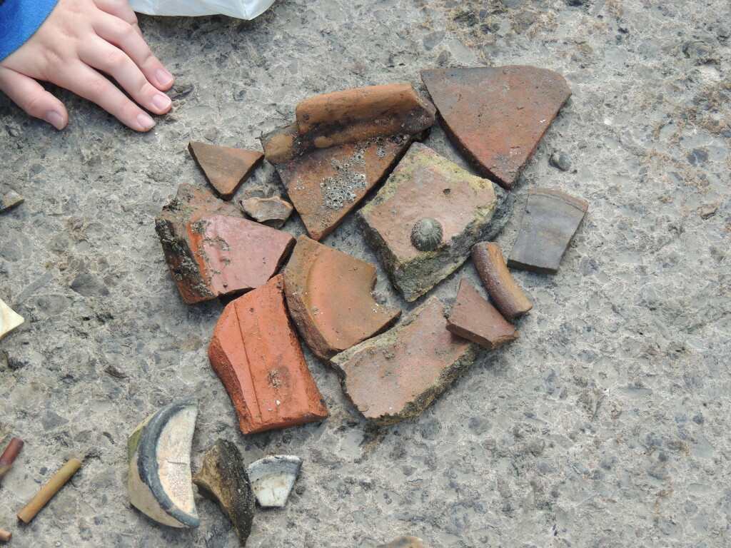 A collection of broken pieces of pottery is laid out on the floor