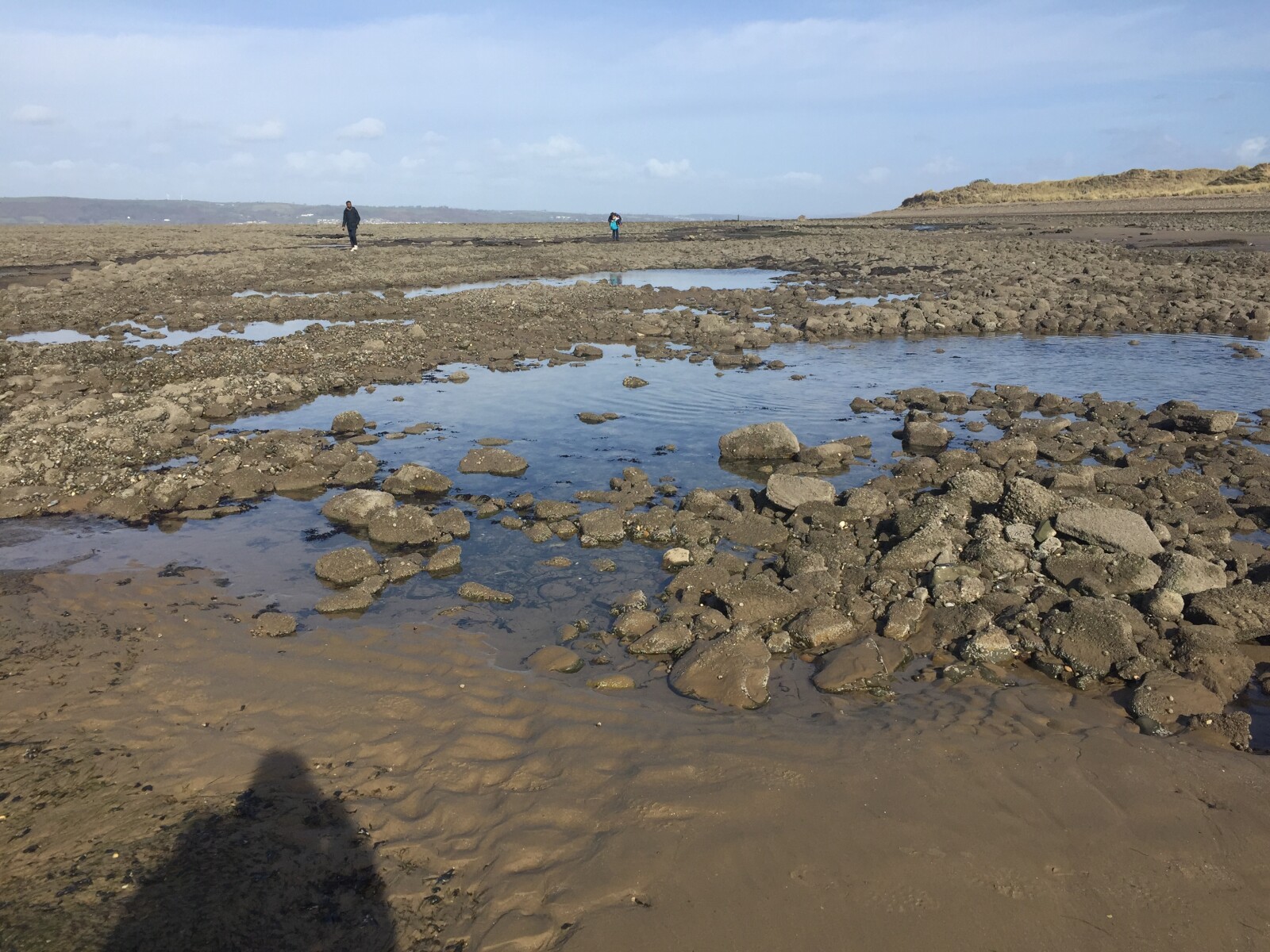 The images shows a beach on a spring day. It is a rocky beach which dates back to the mesolithic era.