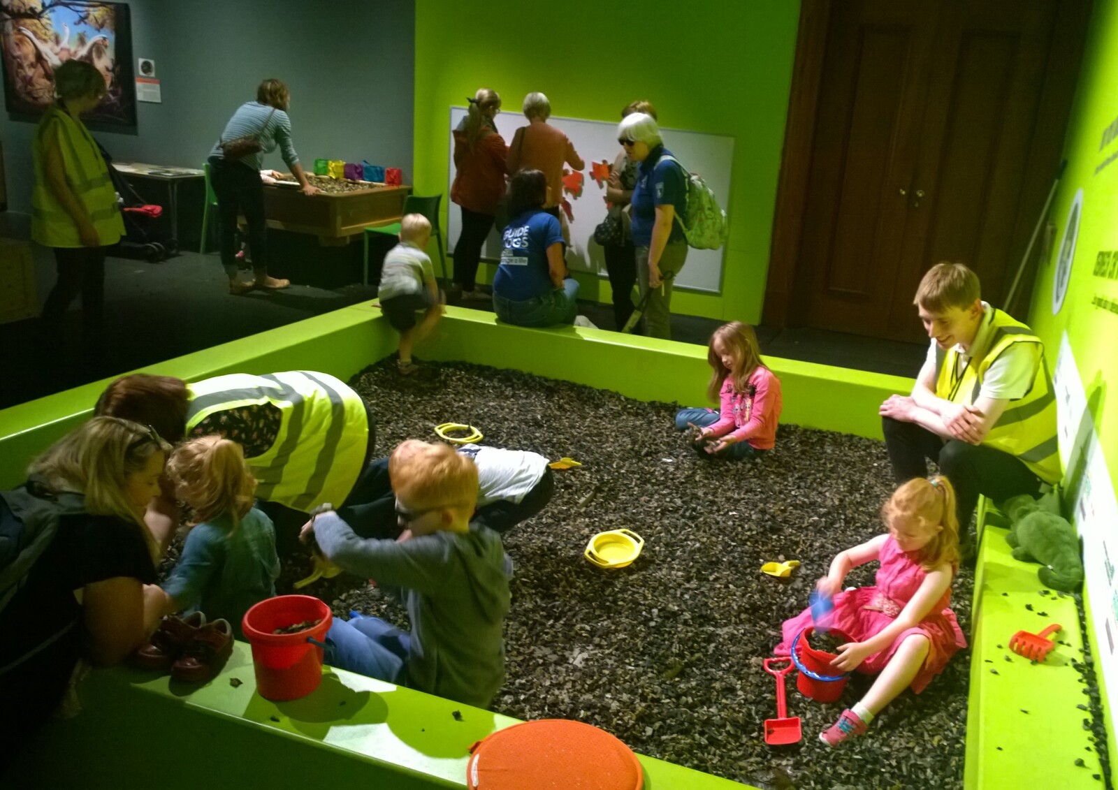 Photograph of children and museum staff playing in the dinosaur dig pit in the dinosaur babies exhibition