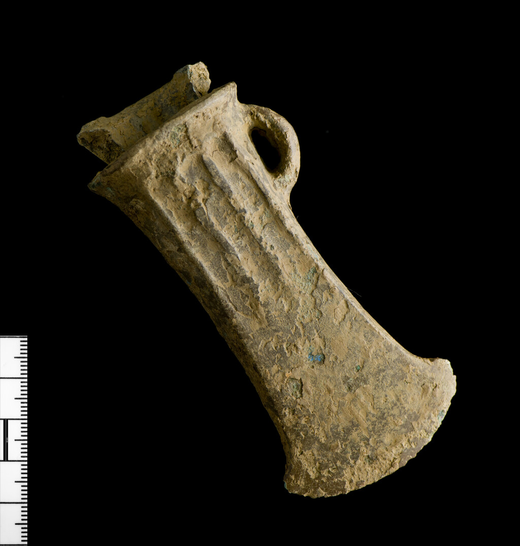 Picture of a Bronze Age ribbed socketed axe with another axe bent and inserted into the mouth of it