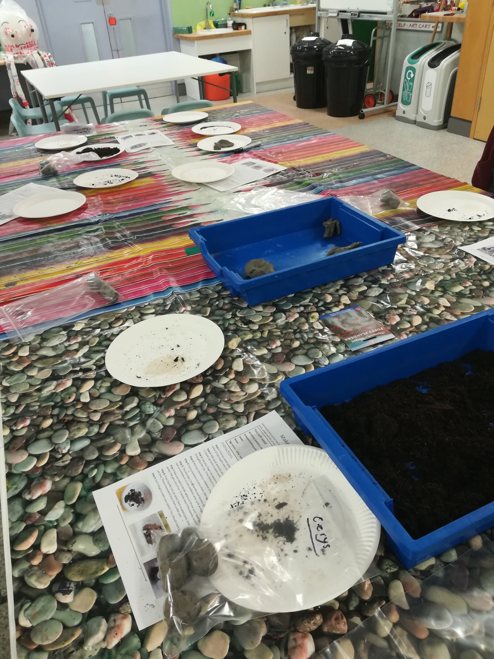 Photograph of tabletop with containers of clay and soil, where visitors were making seed bombs
