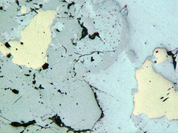 Reflected light (plane polarized light) microscope image showing brownish-grey tetrahedrite (bottom left) contrasting with white galena (top right), yellow chalcopyrite and mid-grey bournonite (top middle). x100 magnification. Darren mine. NMW 90.14G.M.56