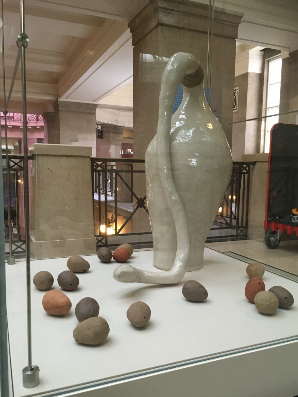 Photo of a large ceramic vase and 15 small ceramic onions, in a display case