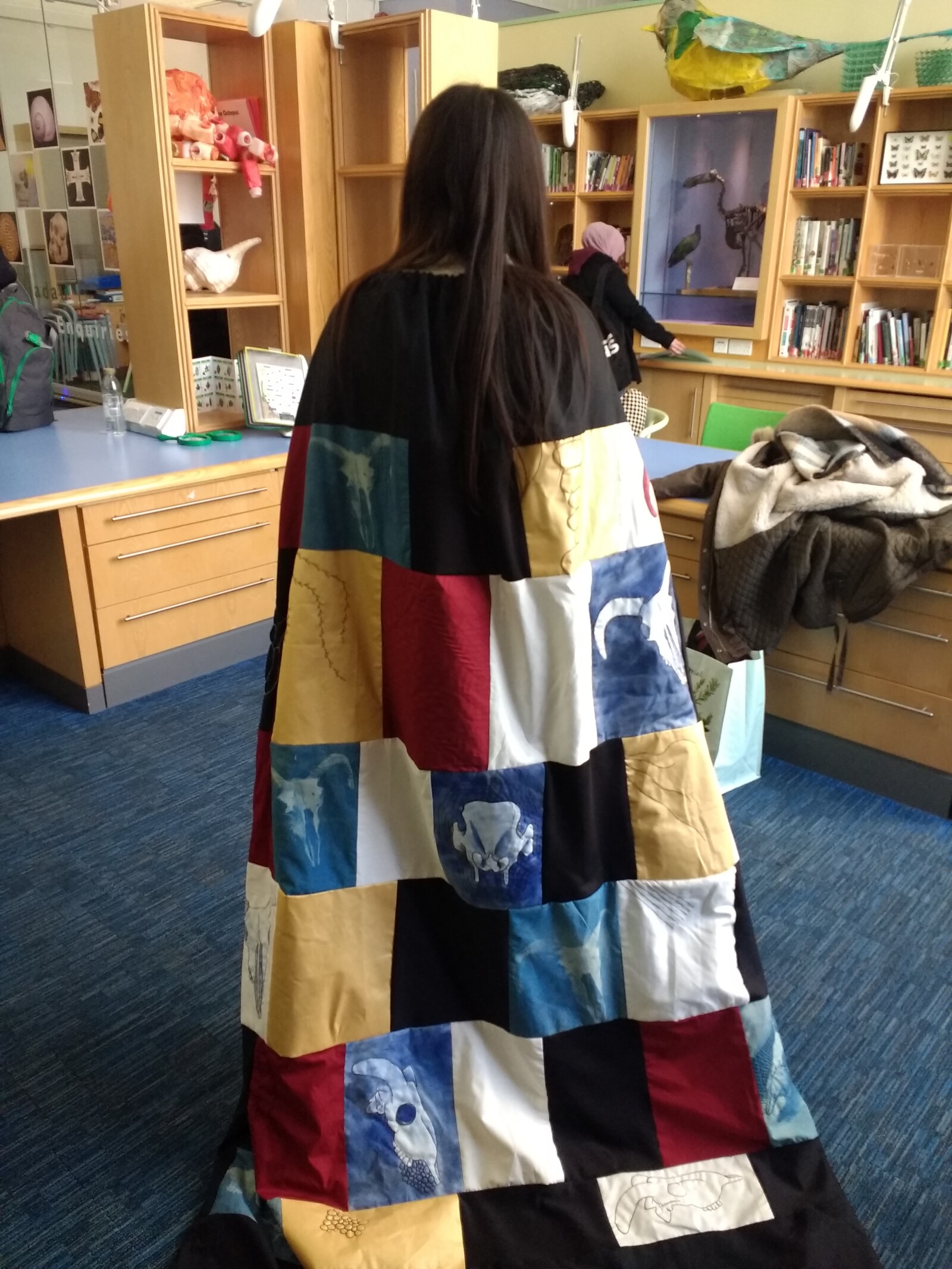 Photo of a student wearing a textile cape containing images of animal skulls