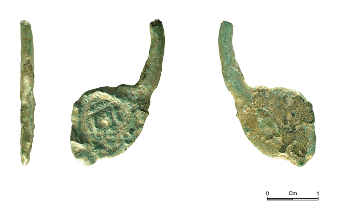 The decorated end of a small, almost circular brooch.