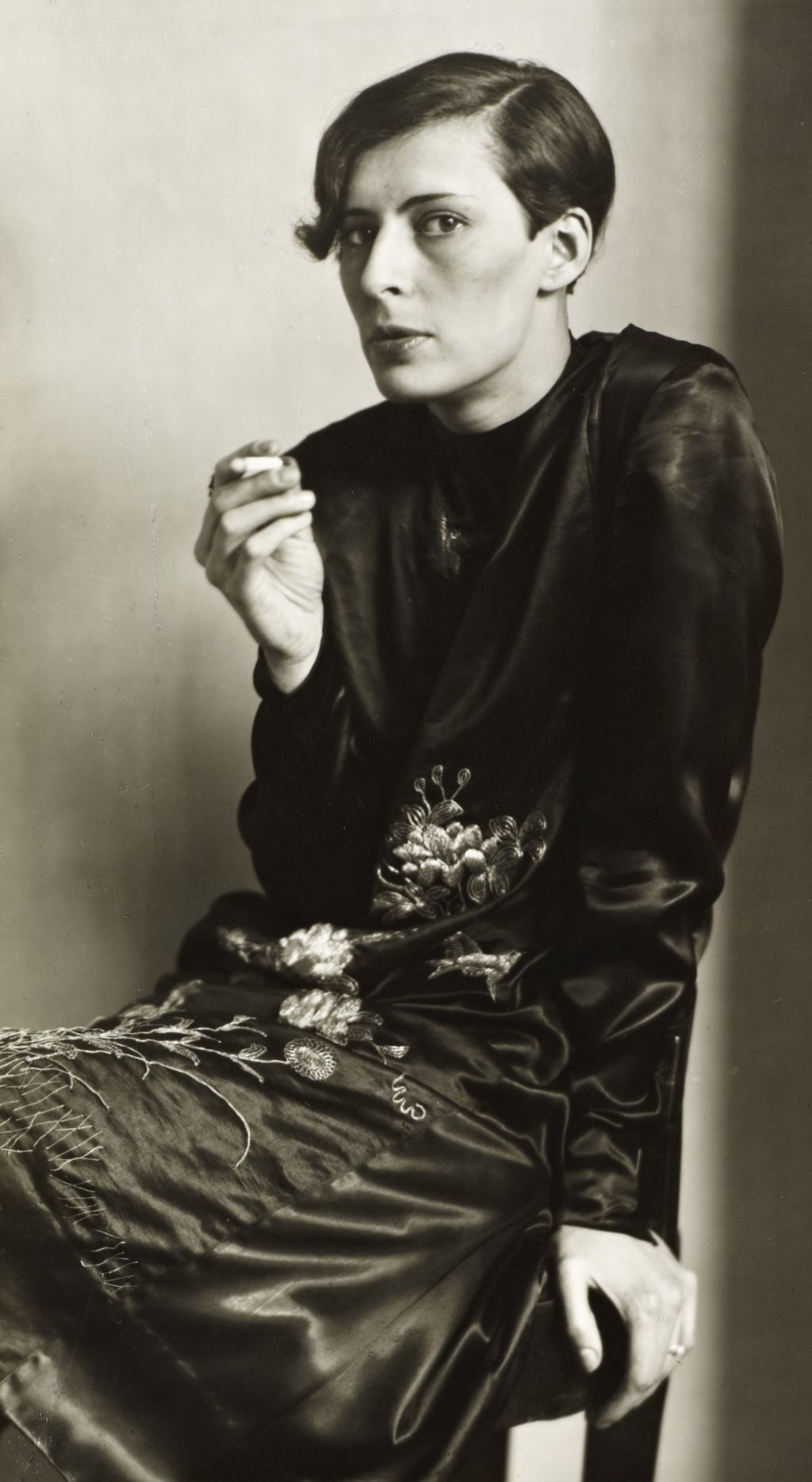 A black and white photo of a woman looking at the camera and smoking a cigarette
