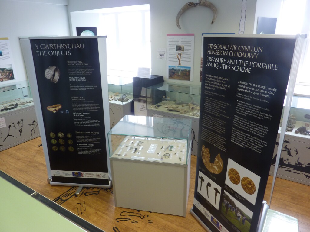 Objects in a small museum case, flanked by two pull-up banners.