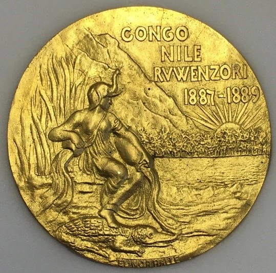 photograph of the reverse of the gold medal showing a female figure in a helmet sat on the bank of a river