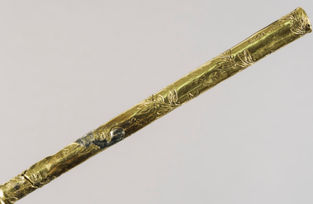 A close-up view of the gold conductor's baton