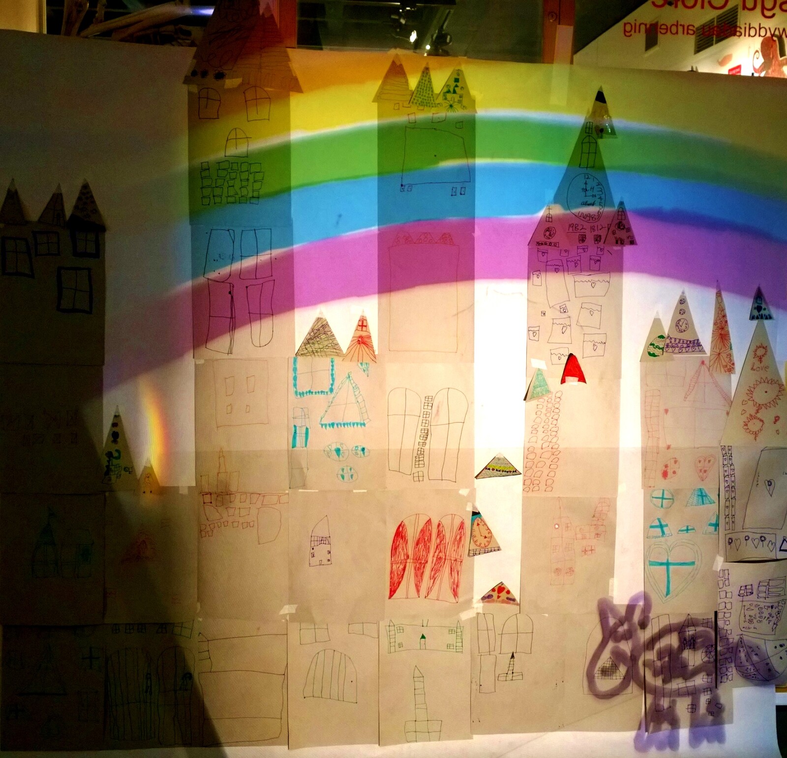 A cathedral drawn by school pupils on paper, with a rainbow projected over the top