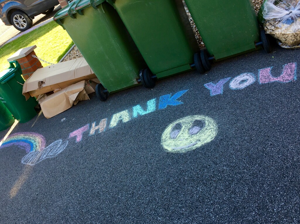 Chalk drawings and THANK YOU written on the floor in front of a row of bins