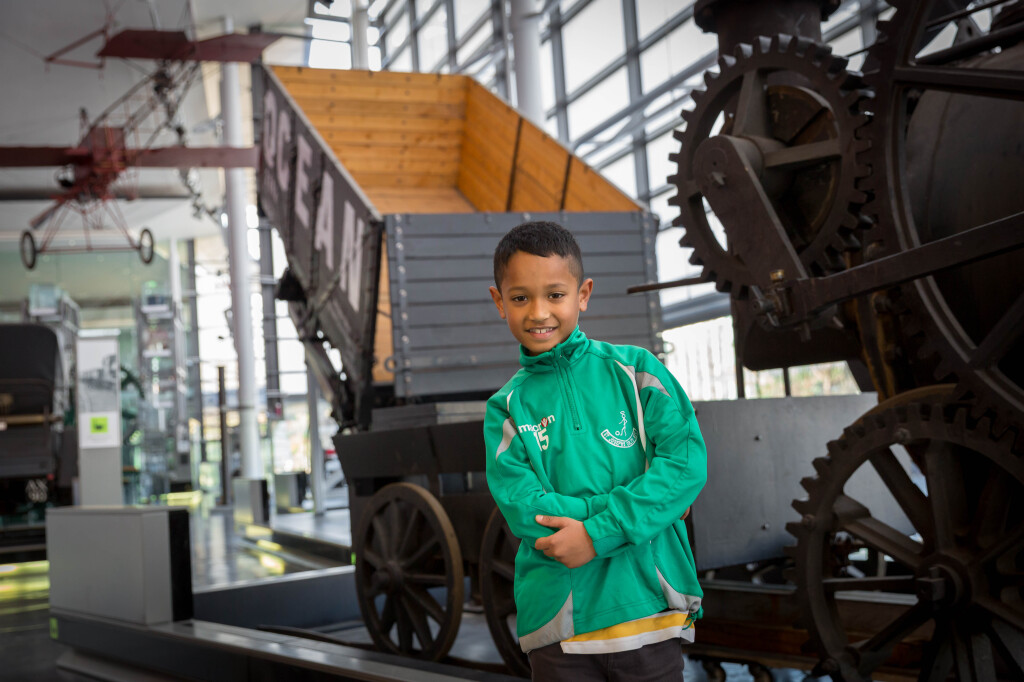 A child stands in front of a railway wagon in Swansea Museum