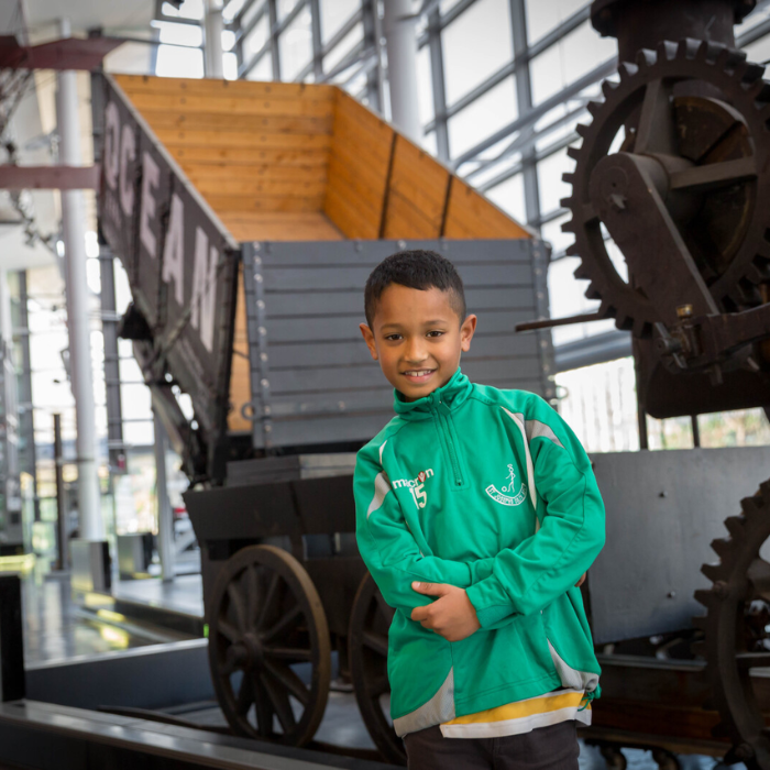 A child stands in front of a railway wagon in Swansea Museum