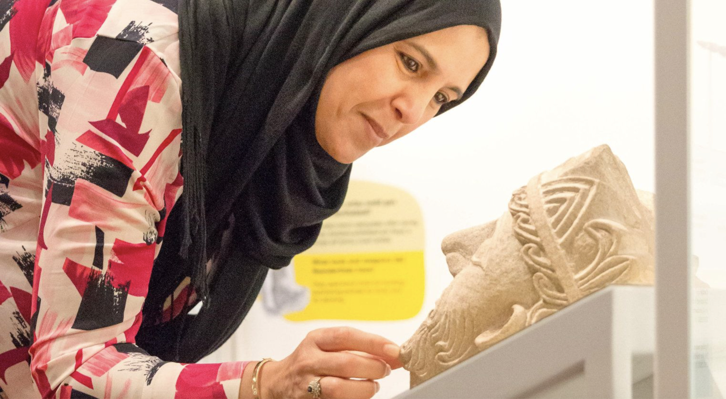 Visitor looking at a carved stone head in a museum display