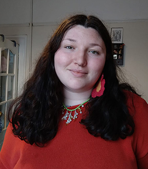 Profile headshot of Youth facilitator standing in living room looking at camera