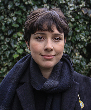 Profile headshot of youth facilitator in front of a hedge outside